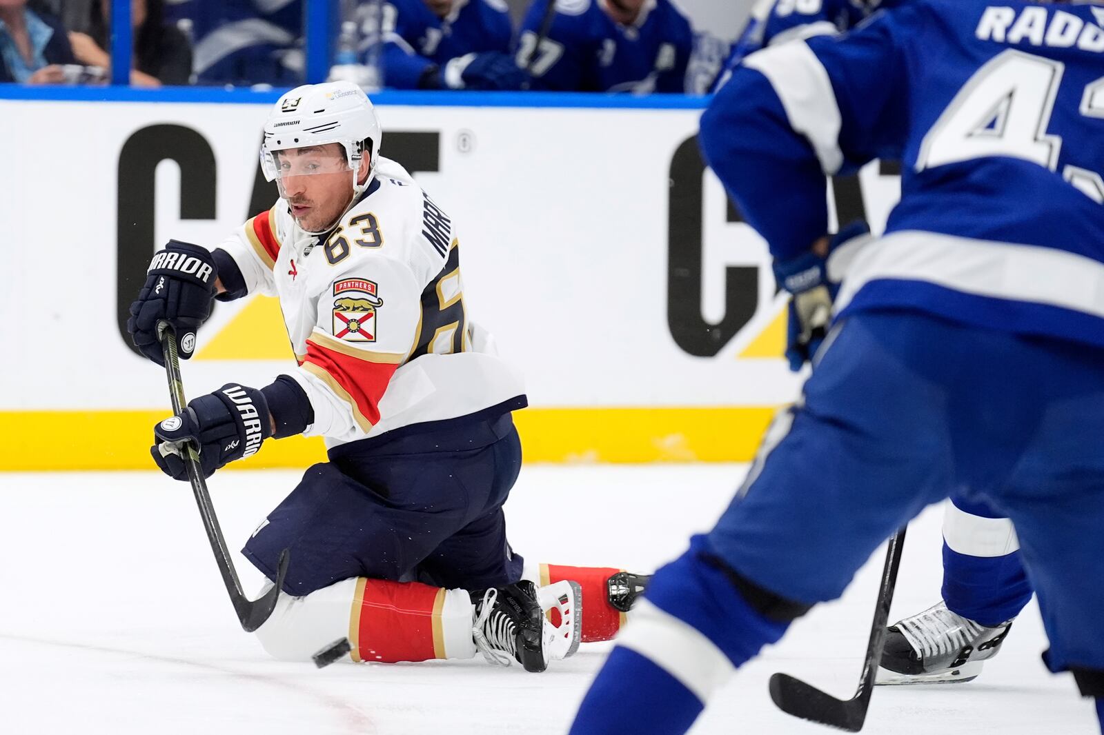 Florida Panthers center Brad Marchand (63) passes the puck after getting knocked down during the first period in Game 1 of an NHL hockey Stanley Cup first-round playoff series, against the Tampa Bay Lightning Tuesday, April 22, 2025, in Tampa, Fla. (AP Photo/Chris O'Meara)