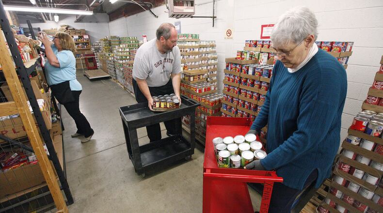 Administrators at the Xenia Area Fish Food Pantry restock with donated canned goods in May 2019. From left to right are Brenda Donahue, director of operations, Mike Reeves vice president and Gail Matson board president. The pantry is seeking EDGE grant money from Greene County and other partners to relocate to a larger county-owned building in Xenia that would nearly triple the amount of space for the operation. TY GREENLEES / STAFF