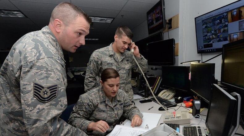 Senior Airman Jenna Kuzava, 88th Security Forces Squadron alarm monitor, consults a building custodian’s list and verifies the building’s location, while 88 SFS electronic systems non-commissioned officers in charge, Tech Sgt Matthew Gillette (left) and Staff Sgt. Joshua Modlin (right) assist during an alarm activation at Wright-Patterson Air Force Base on May 16. The 88 SFS maintains alarm systems on base, as well as information technology issues for their squadron. (U.S. Air Force photo/Michelle Gigante)