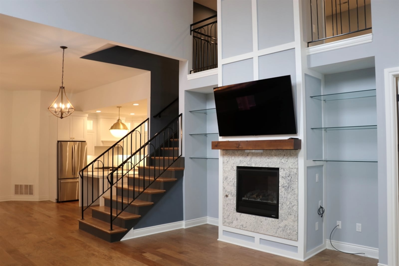 An open wooden staircase with wrought-iron railing divides the dining area from the great room. Windows fill the tall wall, allowing natural light to filter into the upstairs loft. A two-story fireplace has a Heat-and-Glo gas fireplace. CONTRIBUTED BY KATHY TYLER