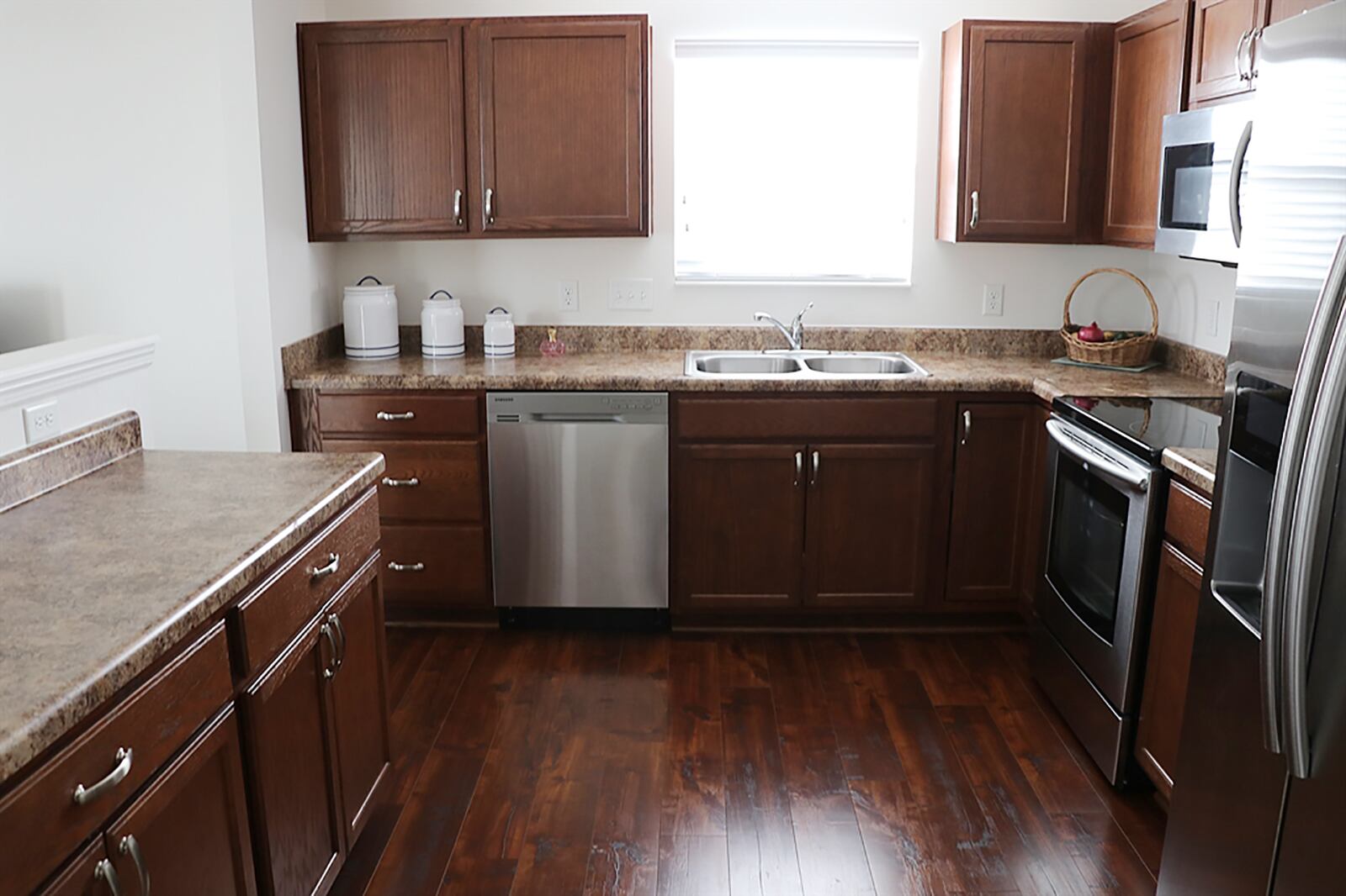 Kitchen cabinetry and counter space fills two walls and surrounds appliances. There is a window above the double sink, and there is a walkway access from the kitchen to the breakfast room. CONTRIBUTED PHOTO BY KATHY TYLER
