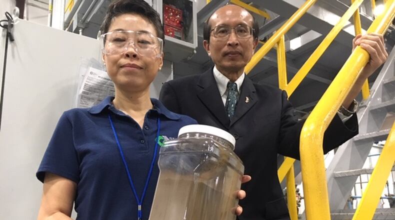 Global Graphene Group (G3) co-founders Aruna Zhamu (left) and Bor Jang, holding a jar of graphene material that will comprise a battery anode. G3 says graphene will help batteries of both smart phones and electric vehicles charge faster, last longer and dissipate heat more completely. This photo was taken at G3’s McCook Avenue production facility. THOMAS GNAU/STAFF