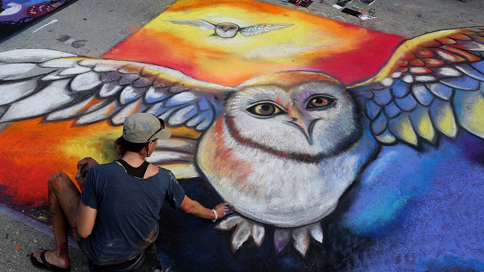 Carrie Bennett, of Lighthouse Point, spreads chalk on the pavement as she paints the movie ''Legend of the Guardians: The Owls of Ga'Hoole.'' (Greg Lovett/The Palm Beach Post)