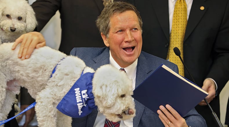 Sammy a Bichon eats a dog snack that was on the table right after Gov. John Kasich signed a bill into law that establishes new regulations on the care and treatment of animals housed in large-scale establishments at the Capital Area Humane Society in Columbus, January 10, 2013. Sammy and her owner Barbara McKelvey came down from Wadsworth, Ohio for the signing of the bill. (Dispatch photo by Kyle Robertson