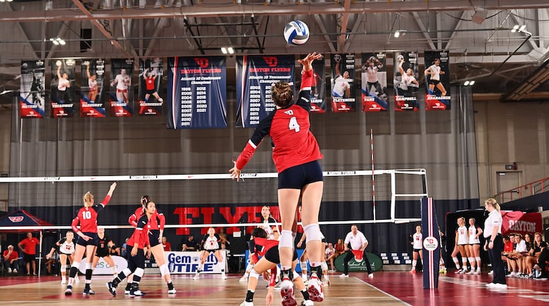 Lexie Almodovar, center, of the Dayton volleyball team, serves during a match against Western Kentucky at the Frericks Center on Friday, Aug. 24, 2023. Photo courtesy of University of Dayton Athletics