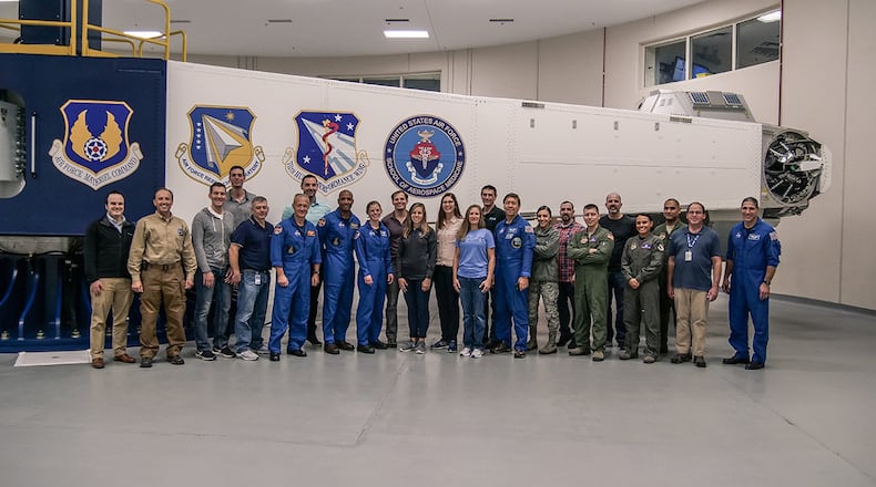 NASA and Boeing astronauts pose in the Air Force Research Laboratory’s centrifuge facility Nov. 1-2, 2018. AFRL’s centrifuge spins with one of the astronauts inside. This centrifuge is the Department of Defense’s only human-rated centrifuge with interchangeable cockpits, a capability that enabled NASA and AFRL engineers to create the astronauts’ cockpit. (U.S. Air Force photo/Keith Lewis)