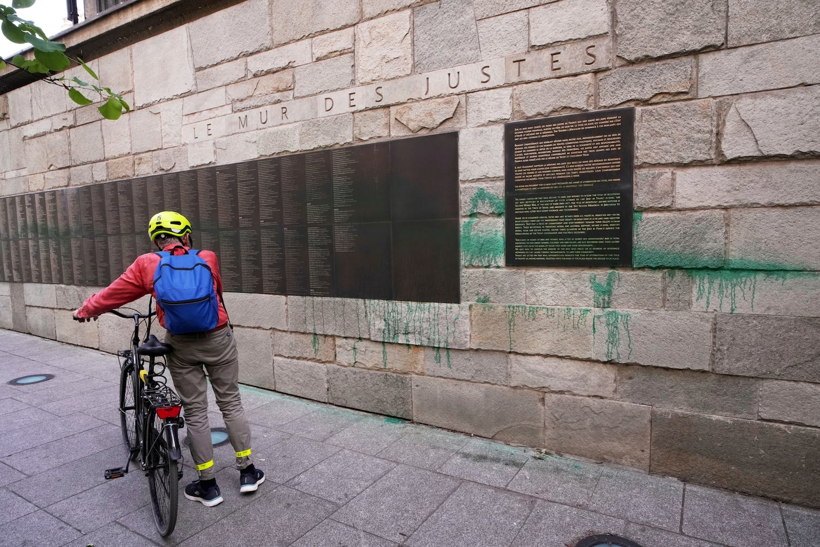 A cyclist looks at Paris' Shoah Memorial defaced with green paint after several Jewish sites across the capital were defaced with green paint. Saturday, May 31, 2025 in Paris. (AP Photo/Aurelien Morissard)
