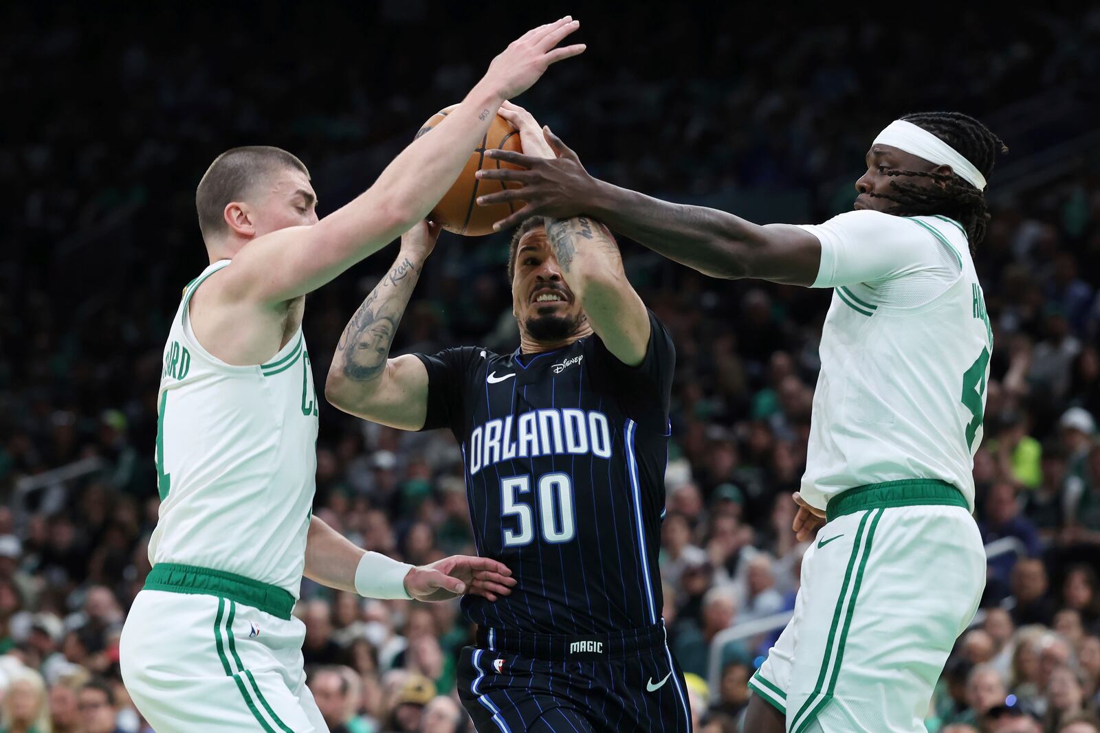Orlando Magic's Cole Anthony (50) drives between Boston Celtics' Payton Pritchard (11) and Jrue Holiday (4) during the second half in Game 1 of a first-round NBA playoff basketball series Sunday, April 20, 2025, in Boston. (AP Photo/Michael Dwyer)
