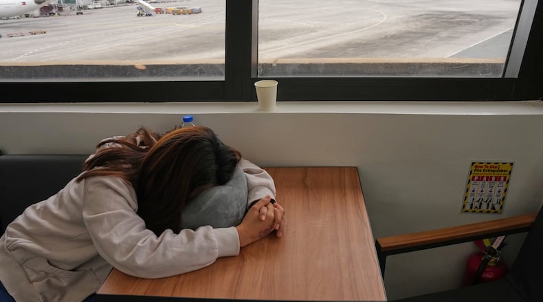 An overseas Filipino worker sleeps as she waits for updates on her cancelled flight to the Middle East at Manila's International Airport, Philippines on Monday, March 2, 2026. (AP Photo/Aaron Favila)