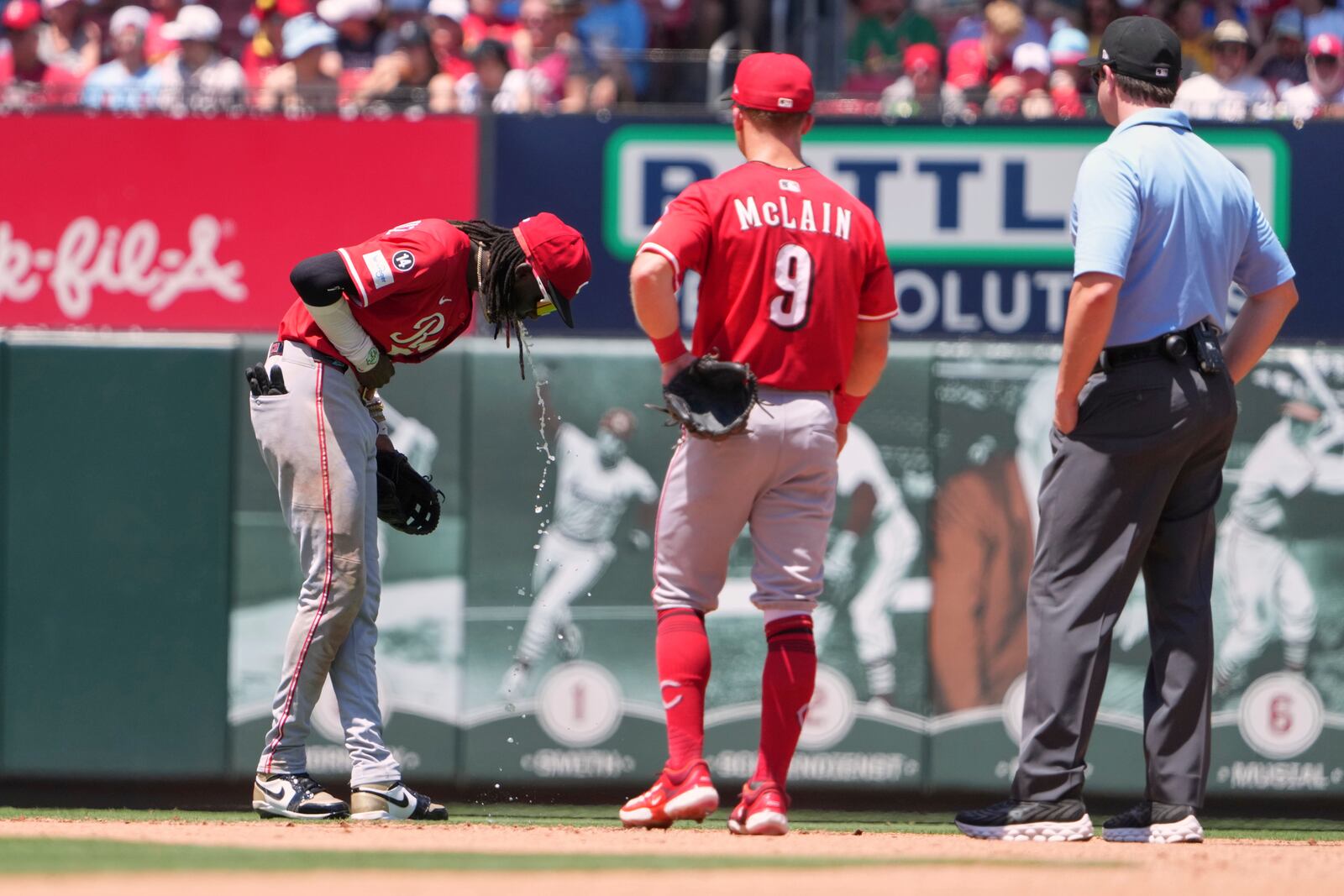 Cincinnati Reds shortstop Elly De La Cruz, left, becomes sick on the field as teammate Matt McLain (9) and second base umpire Adam Beck, right, watch during the fourth inning of a baseball game against the St. Louis Cardinals Saturday, June 21, 2025, in St. Louis. (AP Photo/Jeff Roberson)