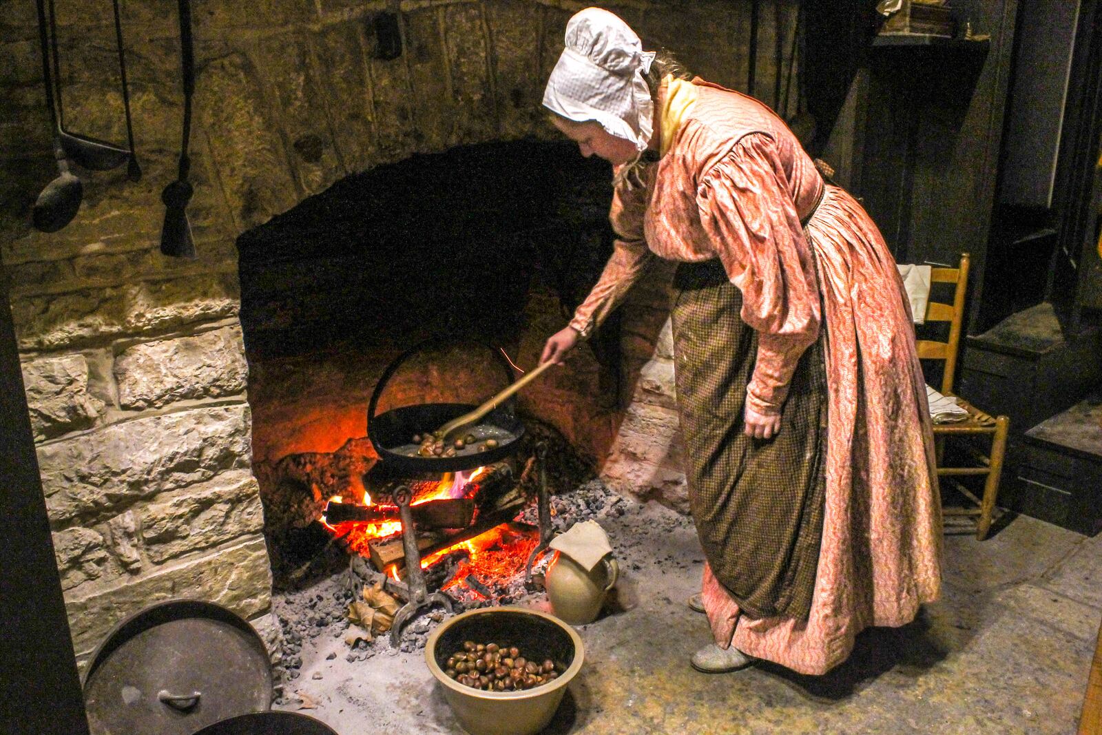 A Carillon Park historic interpreter roasts chestnuts in an iron dish over a roaring fire.