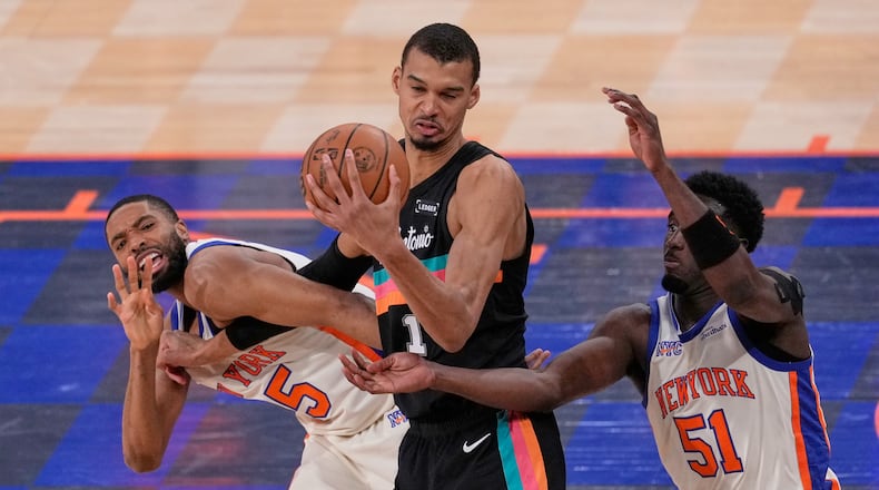 New York Knicks' Mikal Bridges, left, fouls San Antonio Spurs' Victor Wembanyama, center, while Bridges and Mohamed Diawara (51) try to get to the ball during the second half of an NBA basketball game Sunday, March 1, 2026, in New York. (AP Photo/Seth Wenig)