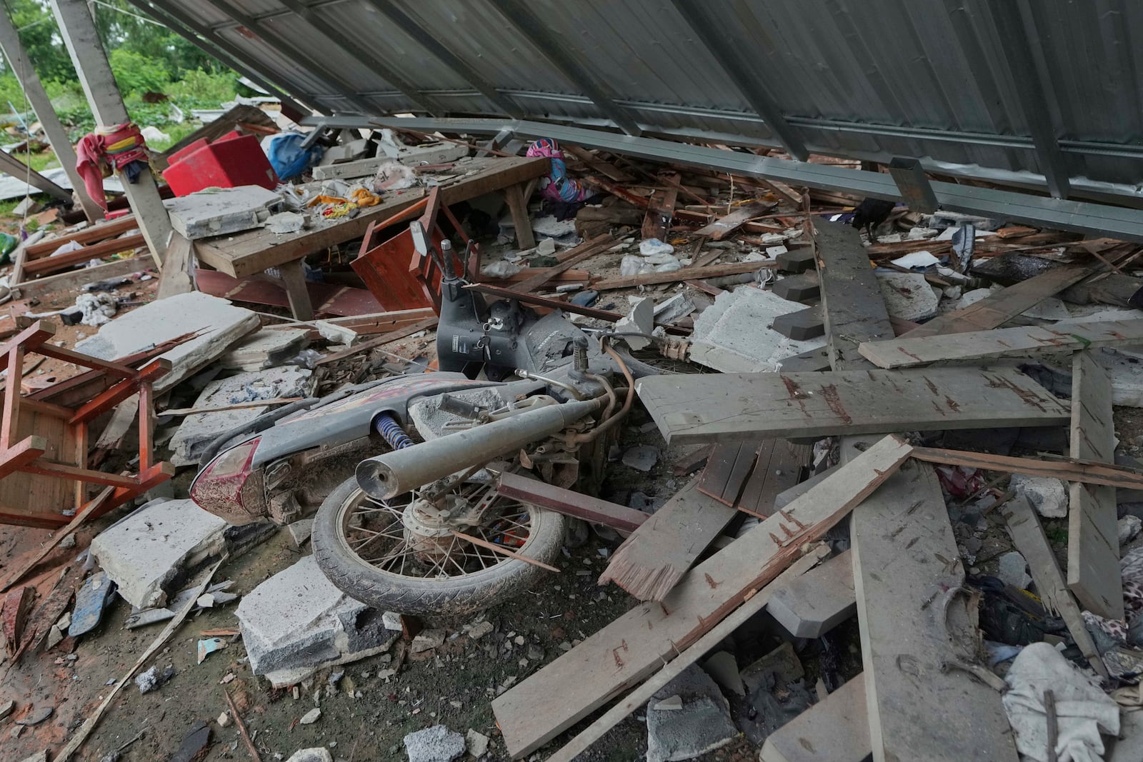 A motorcycle is seen damaged after Cambodia fired artillery shells in Surin Province, Thailand, Sunday, July 27, 2025. (AP Photo/Sakchai Lalit)