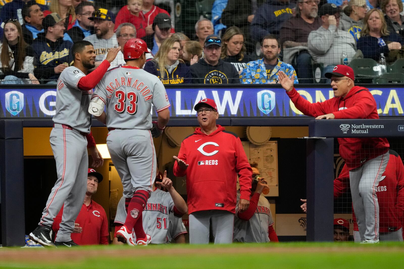 Cincinnati Reds' Christian Encarnacion-Strand (33) is congratulated in the dugout after hitting a solo home run during the fourth inning of a baseball game against the Milwaukee Brewers, Saturday, April 5, 2025, in Milwaukee. (AP Photo/Aaron Gash)