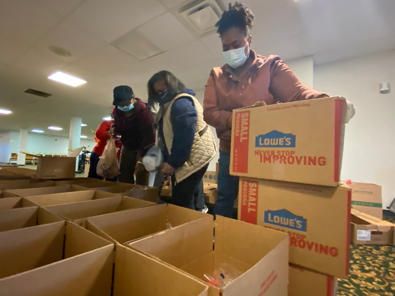 Annette Thomas, right, stacks boxes of food to give out to people in need at St. Luke Missionary Baptist Church on Saturday. Behind her, Ellen Dudley, center, and Lillian Towles, left, place turkeys in boxes.
