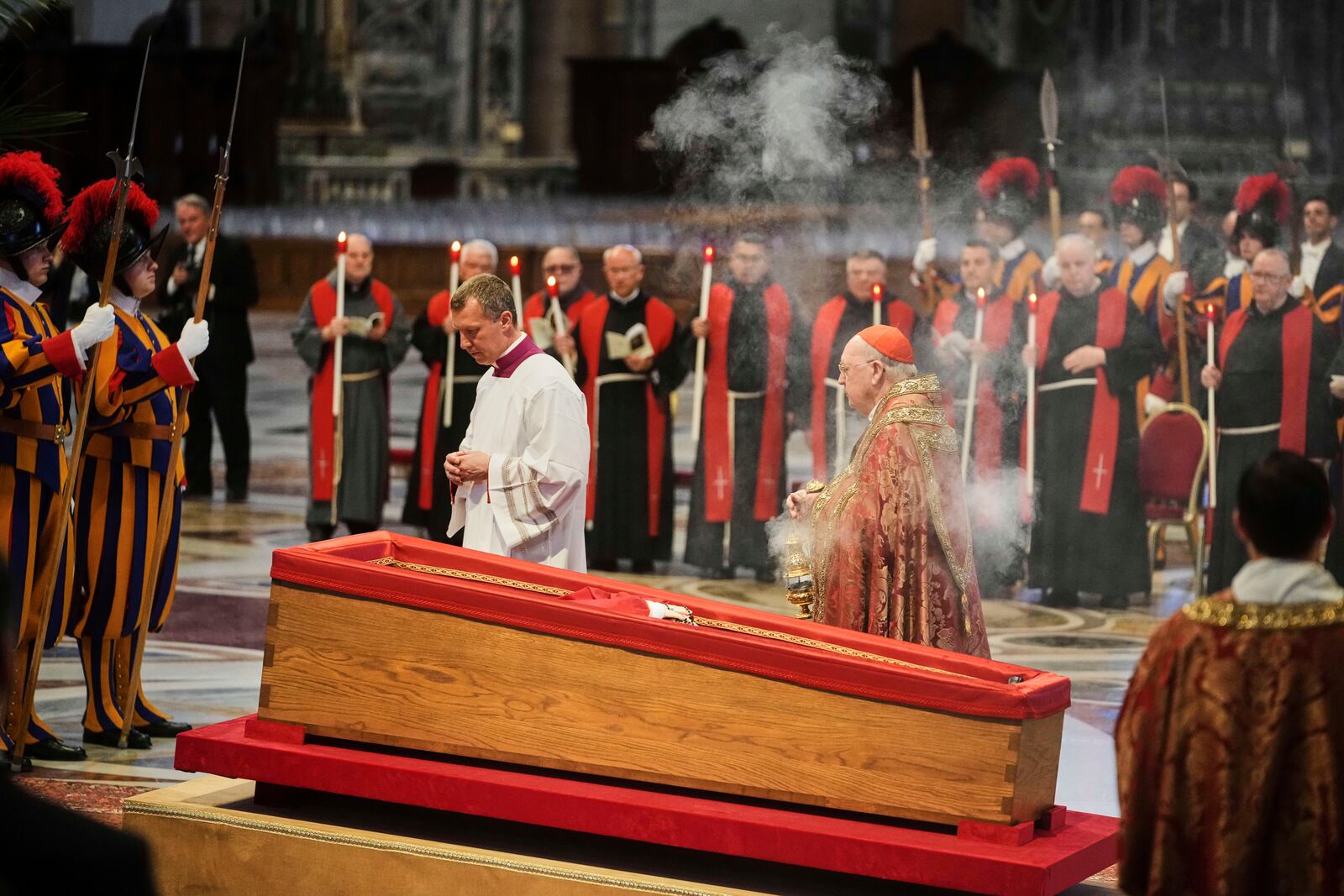 Cardinal Camerlengo Kevin Joseph Farrell, center right, spreads incense around the body of Pope Francis inside St. Peter's Basilica at the Vatican, Wednesday, April 23, 2025, where he will lie in state for three days. (AP Photo/Alessandra Tarantino)