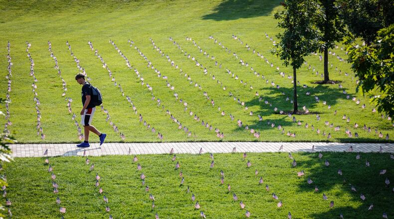 A student walks through a sea of American flags on the University of Dayton Central Mall Friday in memory of the 3,000 people who lost their lives on 9/11 20 years ago. JIM NOELKER/STAFF