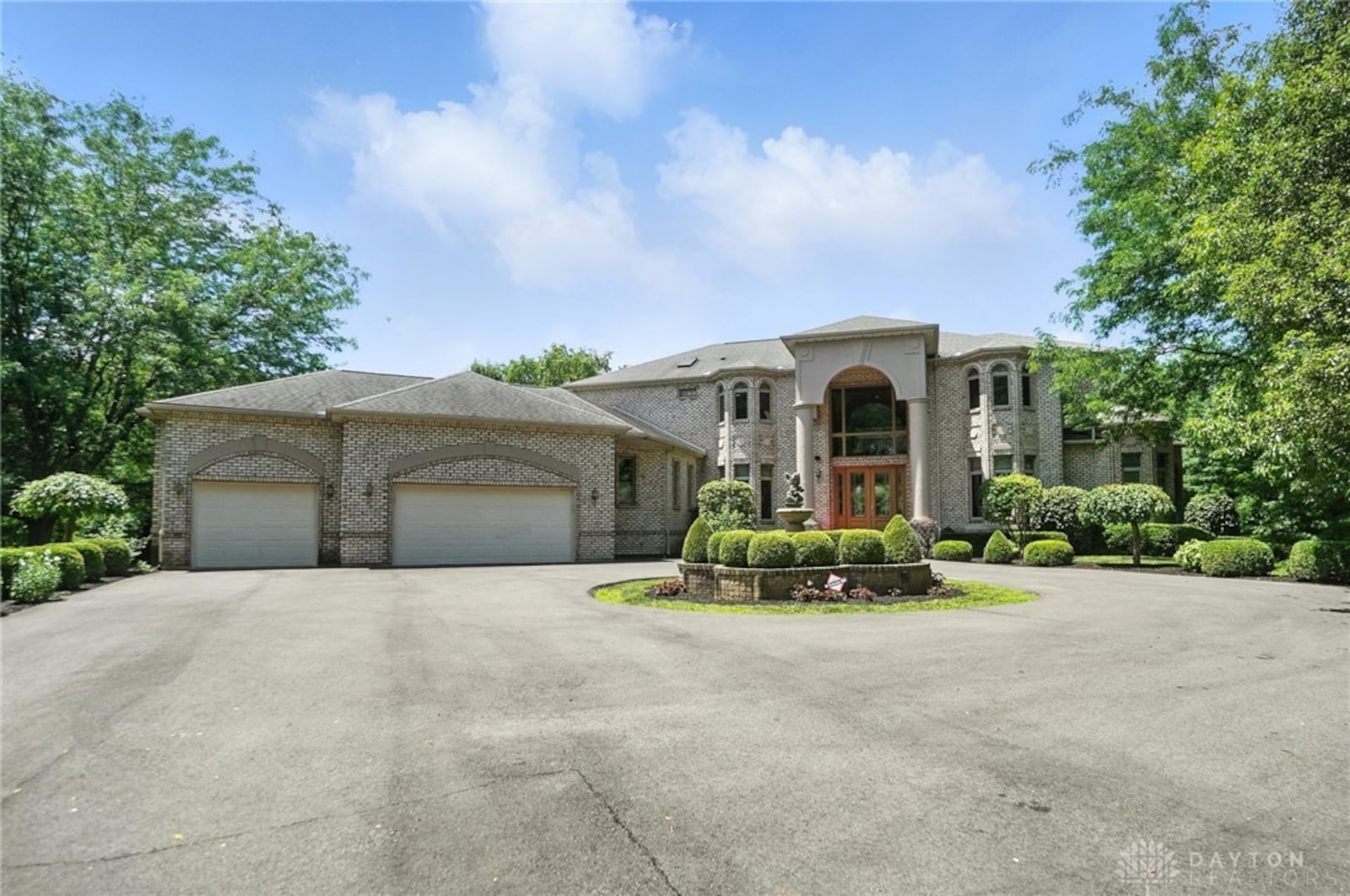 The front of this brick two story home features a two story covered entry, three car attached garage and circular driveway with fountain in the middle. Contributed