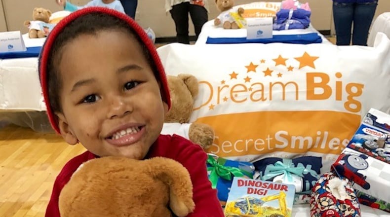 In a Secret Smiles promotional photo, a happy child sits on his new bed at one of the organizations “Day to Dream: events at the Frericks Center  on the UD campus. CONTRIBUTED