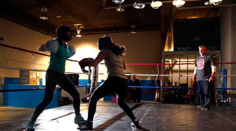 Lauren Amongero of Oakwood and Aimee Pezo of Dayton work out at Drake's Downtown Gym under the watchful eye of gym owner John Drake (right). The two women will meet in a boxing ring during an adult amateur exhibition boxing match Saturday April 8. LISA POWELL / STAFF