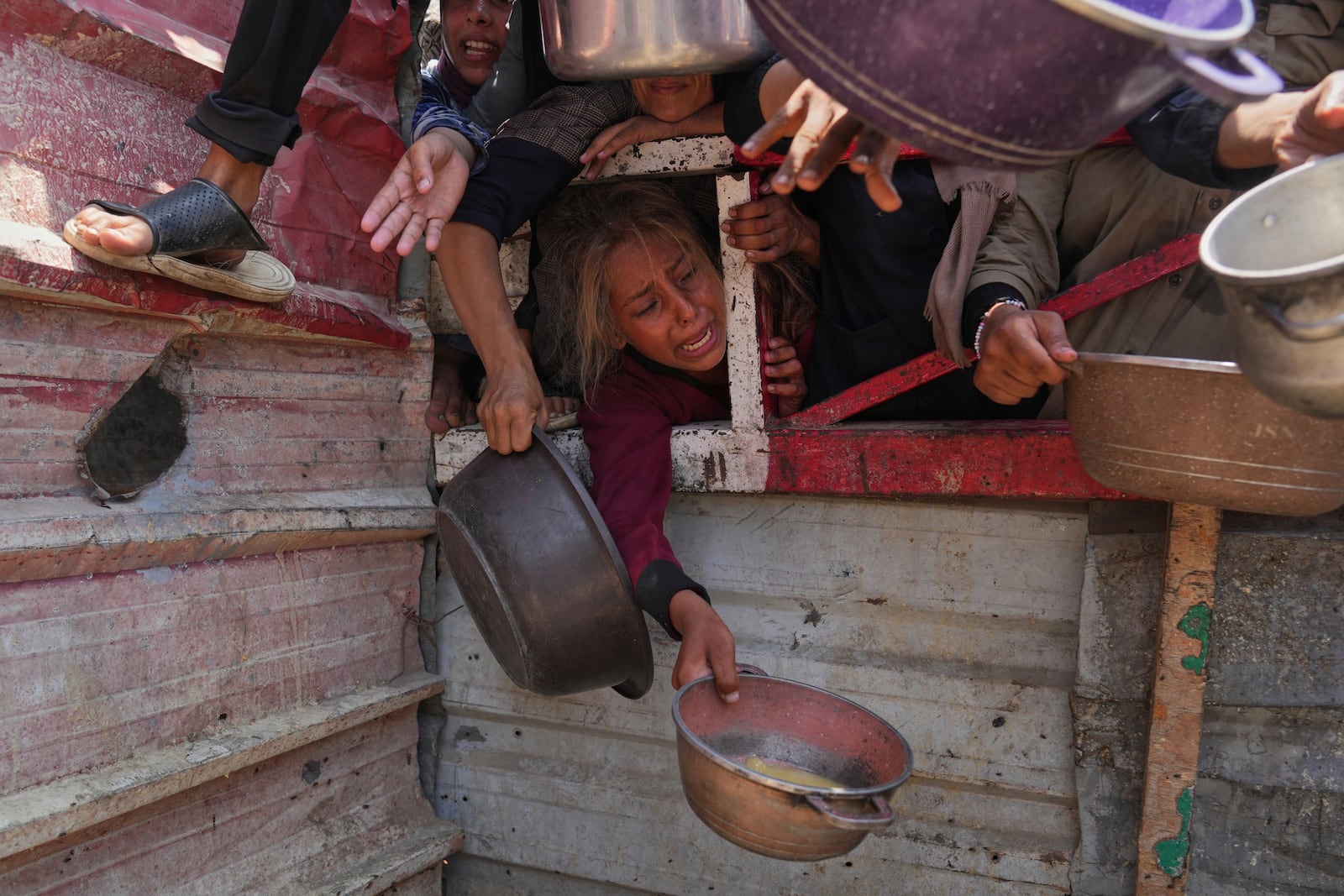 Palestinians struggle to get donated food at a community kitchen, in Gaza City, northern Gaza Strip, Saturday, July 26, 2025. (AP Photo/Abdel Kareem Hana)
