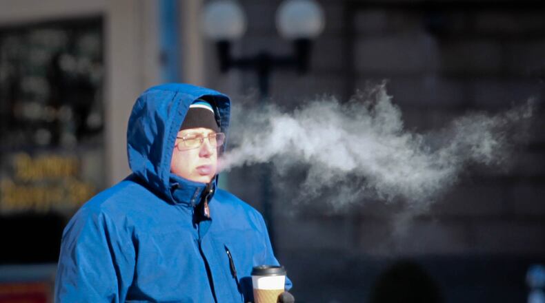 A pedestrian waits in downtown Dayton Monday morning in wind chill as low as -20. JIM WITMER / STAFF