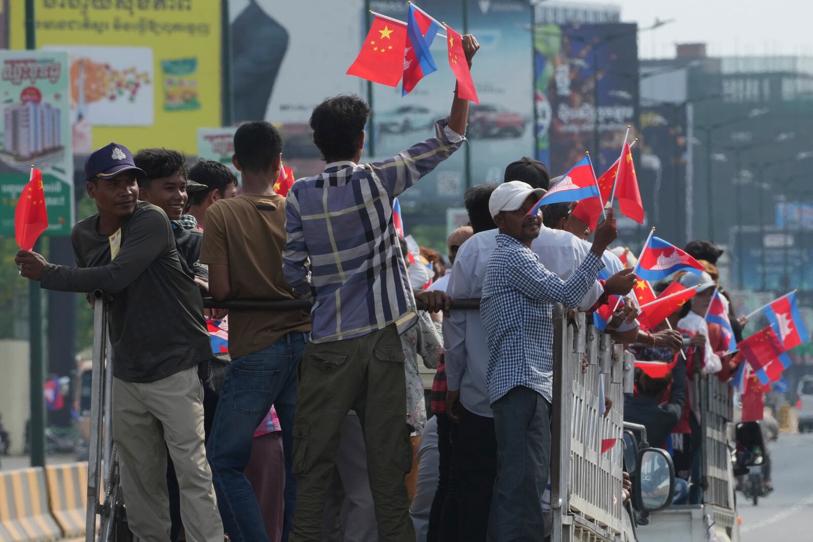 Cambodian villagers stand on the back of trucks as they arrive to welcome Chinese President Xi Jingping's arrival in Phnom Penh, Cambodia, Thursday, April 17, 2025. (AP Photo/Heng Sinith)