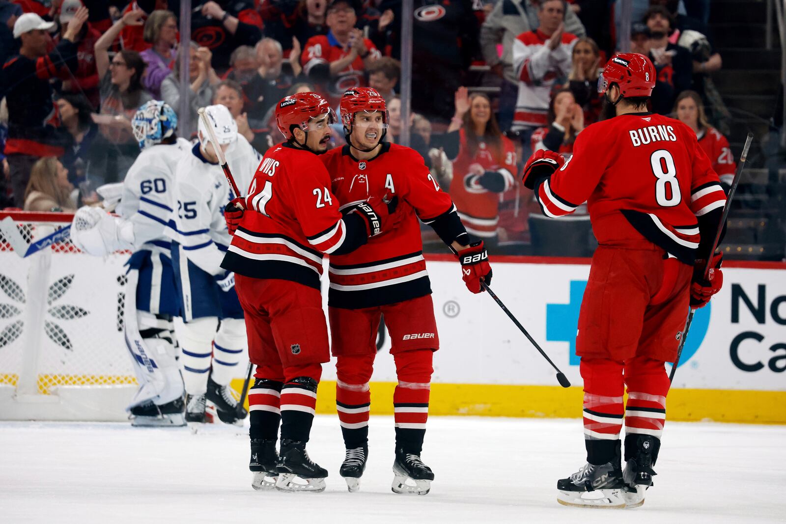 Carolina Hurricanes' Sebastian Aho, center, celebrates his goal against the Toronto Maple Leafs with teammates Seth Jarvis (24) and Brent Burns (8) during the third period of an NHL hockey game in Raleigh, N.C., Sunday, April 13, 2025. (AP Photo/Karl DeBlaker)