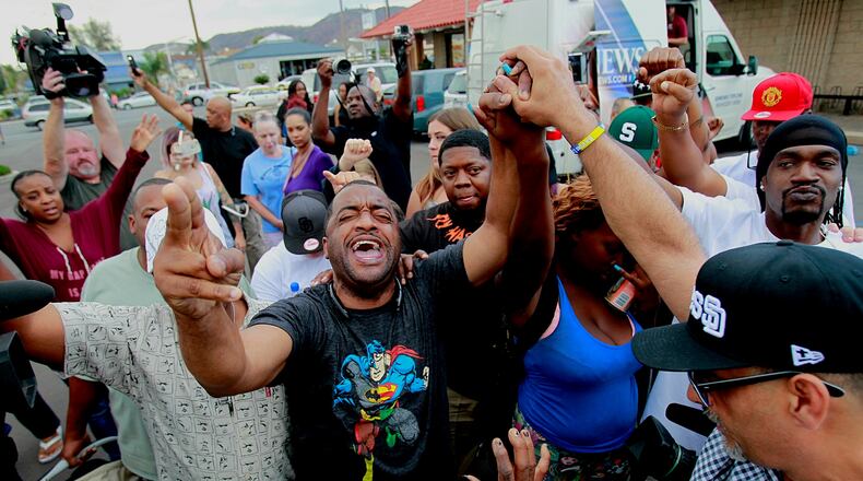 Pastor Russell Bowman, center, prays out loud as people gather at the scene where an African-American man was shot by police in El Cajon, east of San Diego, Calif., Tuesday, Sept. 27, 2016. (Hayne Palmour IV/The San Diego Union-Tribune via AP)