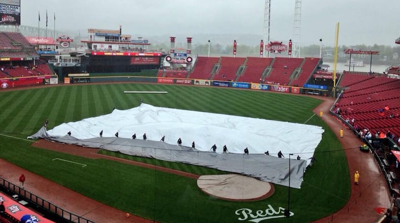 The grounds crew puts the tarp on the field at Great American Ball Park on Saturday. David Jablonski/Staff