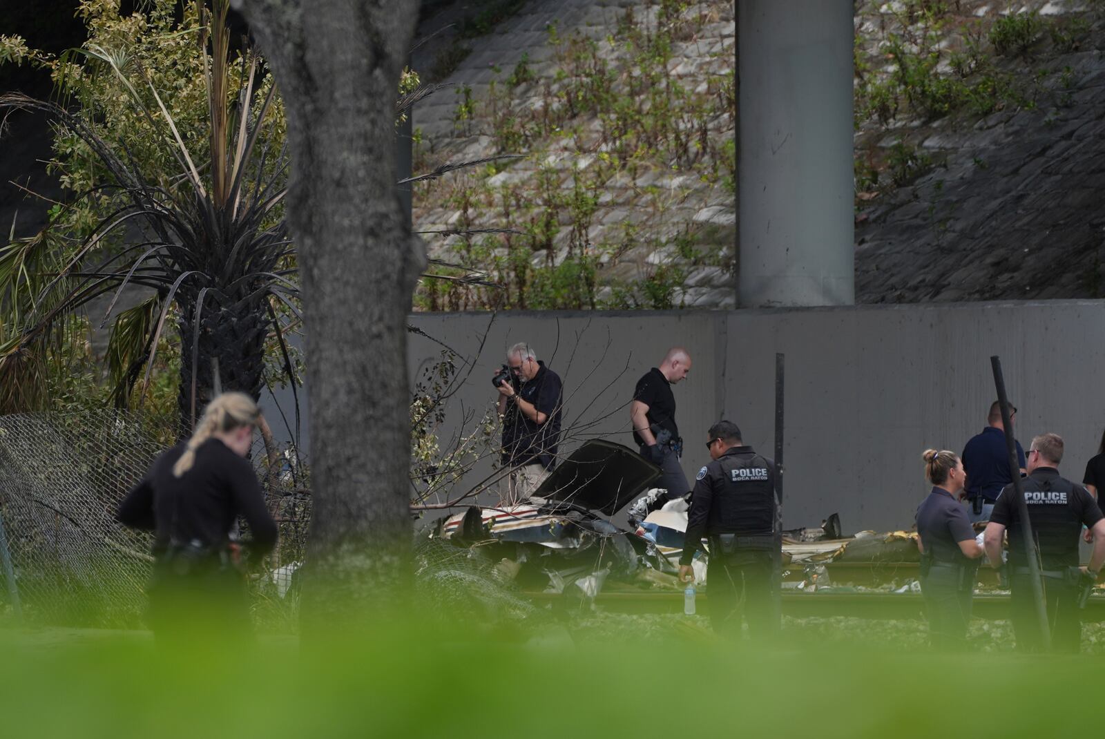 Emergency personnel respond to the area where a small plane crashed on the railroad tracks beneath the overpass near Interstate 95 in Boca Raton, Fla., on Friday, April 11, 2025. (AP Photo/Marta Lavandier)