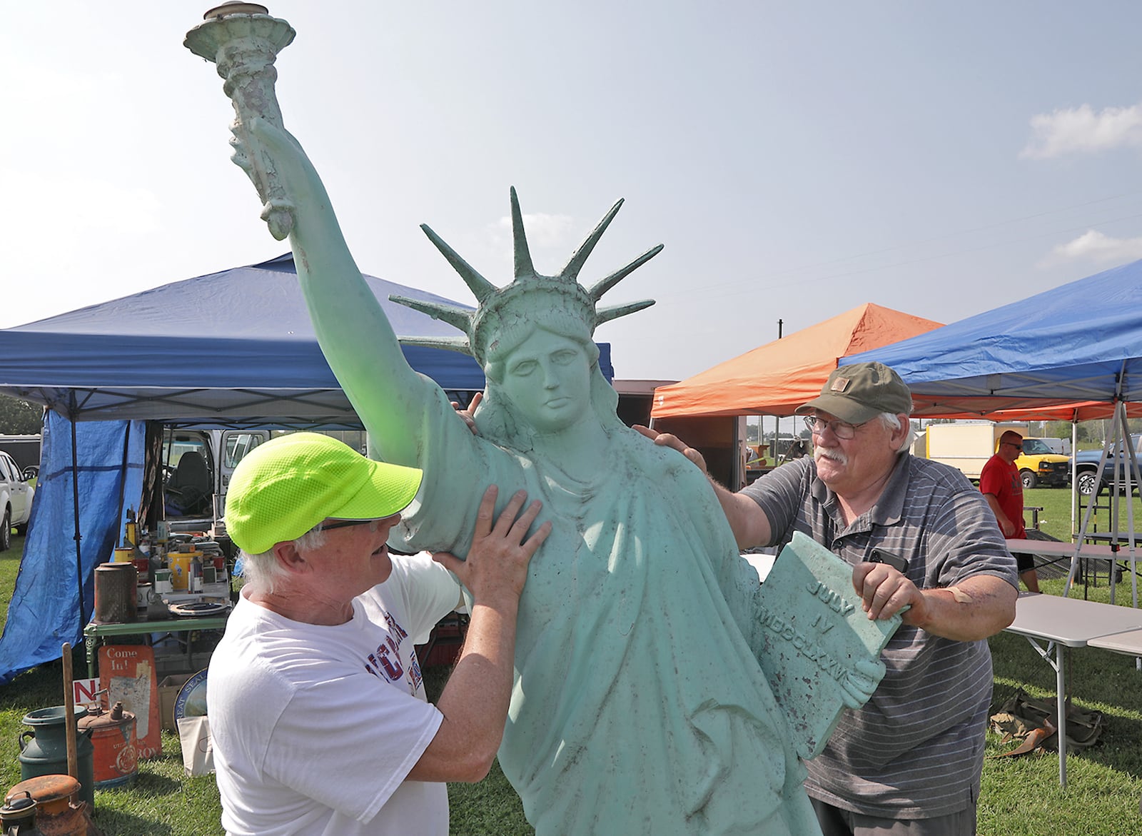 Pat Kennery, left, helps Don Hill set up a replica of the Statue of Liberty in his booth for the Springfield Antique Show & Flea Market at the Clark County Fairgrounds Thursday, August 15, 2022. Vendors were busy getting set up for the start of the giant flea market Friday. The event runs through the weekend. BILL LACKEY/STAFF