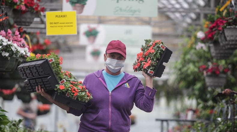 Stockslagers Greenhouse and Garden Center transplanter Heather Rettich moves plants around the garden center Tuesday afternoon. Business has been exceptional for local garden center this Spring. JIM NOELKER/STAFF