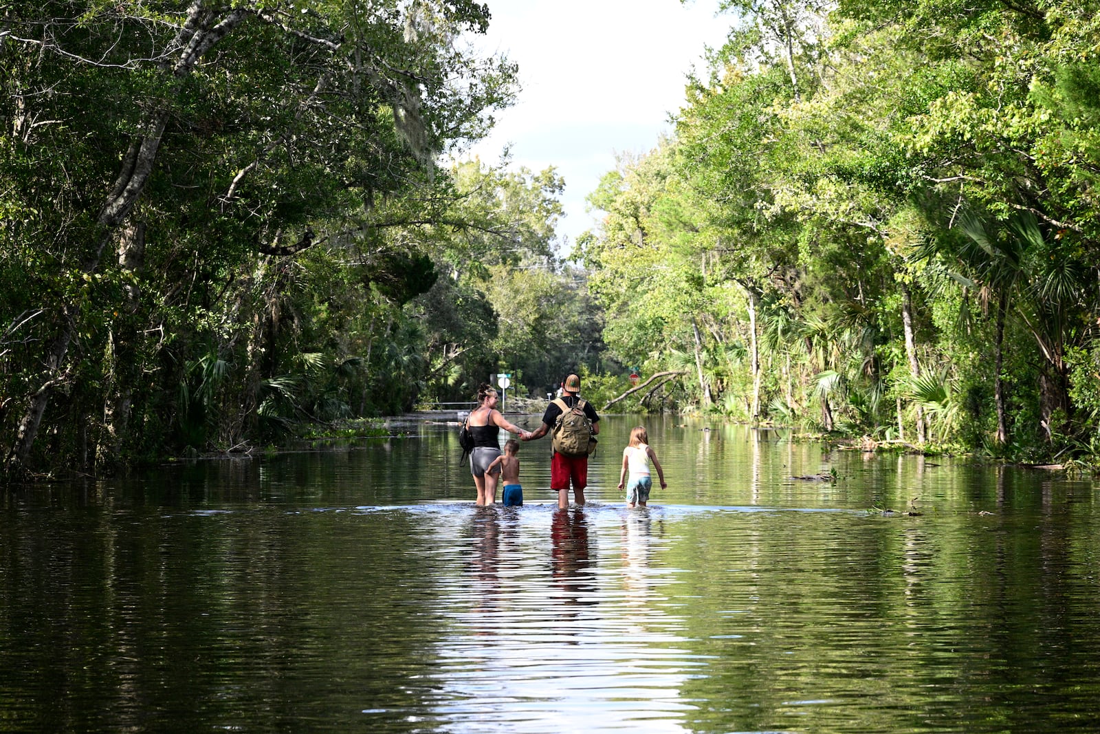 FILE - Dustin Holmes, second from right, holds hands with his girlfriend, Hailey Morgan, while returning to their flooded home with her children Aria Skye Hall, 7, right, and Kyle Ross, 4, in the aftermath of Hurricane Helene, Sept. 27, 2024, in Crystal River, Fla. (AP Photo/Phelan M. Ebenhack, File)