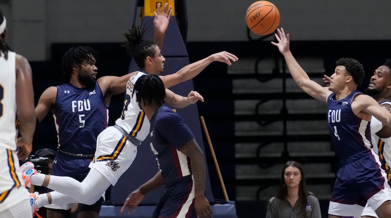 Merrimack guard Javon Bennett, center, passes the ball while pressured by Fairleigh Dickinson's Ansley Almonor (5) and Grant Singleton (4) during the first half of Northeast Conference men's NCAA basketball championship game, Tuesday, March 7, 2023, in North Andover, Mass. (AP Photo/Charles Krupa)