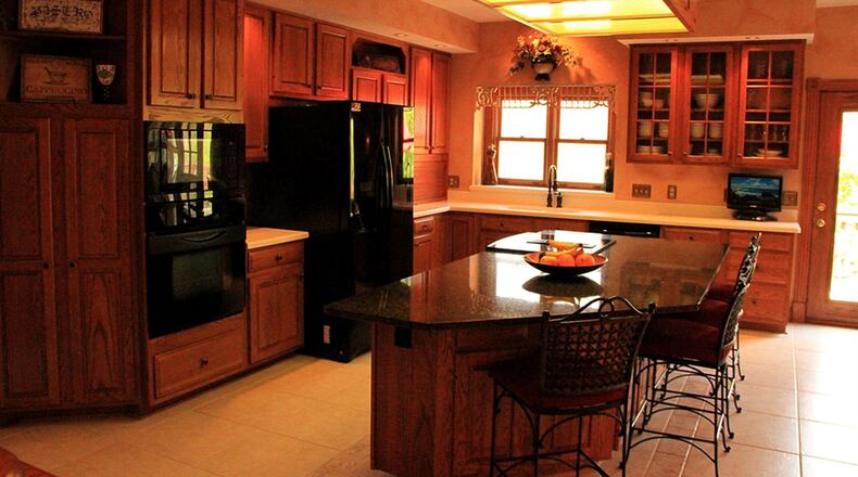 Corian covers the work counters in the kitchen. The granite-topped trapezoidal-shaped island holds a smooth-surface slide-in range with a downdraft vent.
