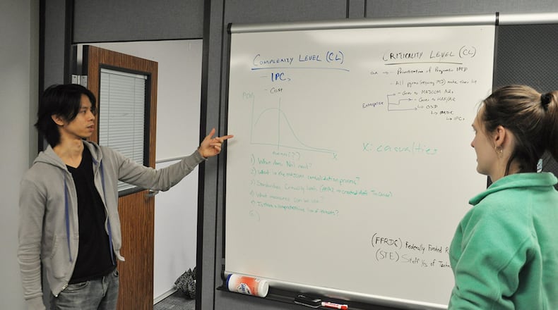 Franco Villongco (left), an operations research analyst with the Air Force Life Cycle Management Center headquartered at Wright-Patterson Air Force Base, confers with colleague Brittany Elliott about a research model Villongco developed. (Contributed photo)