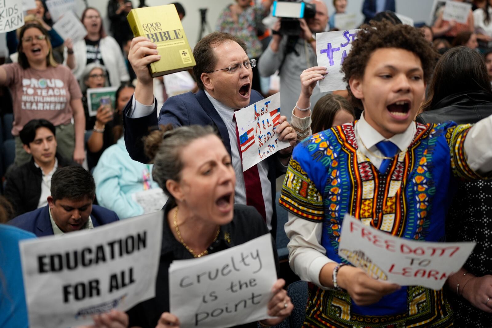 FILE - Justin Wilkins, center, holds a Bible as he yells at lawmakers as a bill that would deny illegal immigrants access to education is passed in a House Education Committee hearing, in Nashville, Tenn., March 26, 2025. (AP Photo/George Walker IV, File)