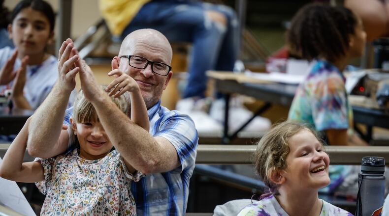 Brynn Miller sits on her dad's, Brandt Miller while daughter Kinzie Miller, right, celebrated the end of the STEM Camp held at Weisenborn Jr. High School Friday July 1, 2022. JIM NOELKER/STAFF
