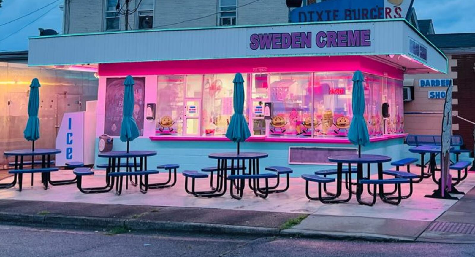 Sweden Creme in Lindenwald, a neighborhood of Hamilton, is painted pink and light blue, and the building is lit up with neon lights at night. Metal tables with built-in benches and umbrellas and picnic-table style seating are available outdoors. A new sign advertises the signature Dixie Burger. The windows are decorated with dancing Dixie Burgers and ice cream cones. CONTRIBUTED
