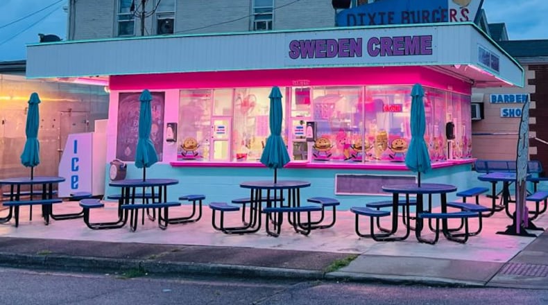 Sweden Creme in Lindenwald, a neighborhood of Hamilton, is painted pink and light blue, and the building is lit up with neon lights at night. Metal tables with built-in benches and umbrellas and picnic-table style seating are available outdoors. A new sign advertises the signature Dixie Burger. The windows are decorated with dancing Dixie Burgers and ice cream cones. CONTRIBUTED