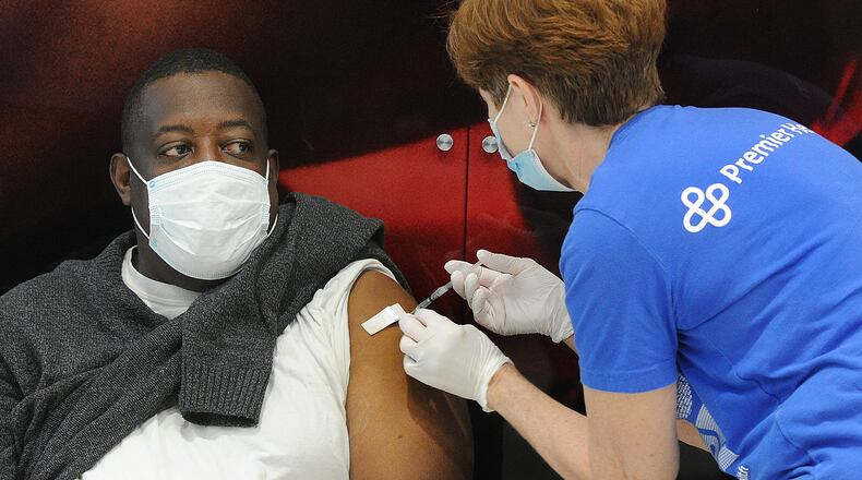 Premier Health administer its 100,000th dose of the COVID-19 vaccine to Tom Long, during Monday’s clinic at the University of Dayton Arena. MARSHALL GORBY\STAFF