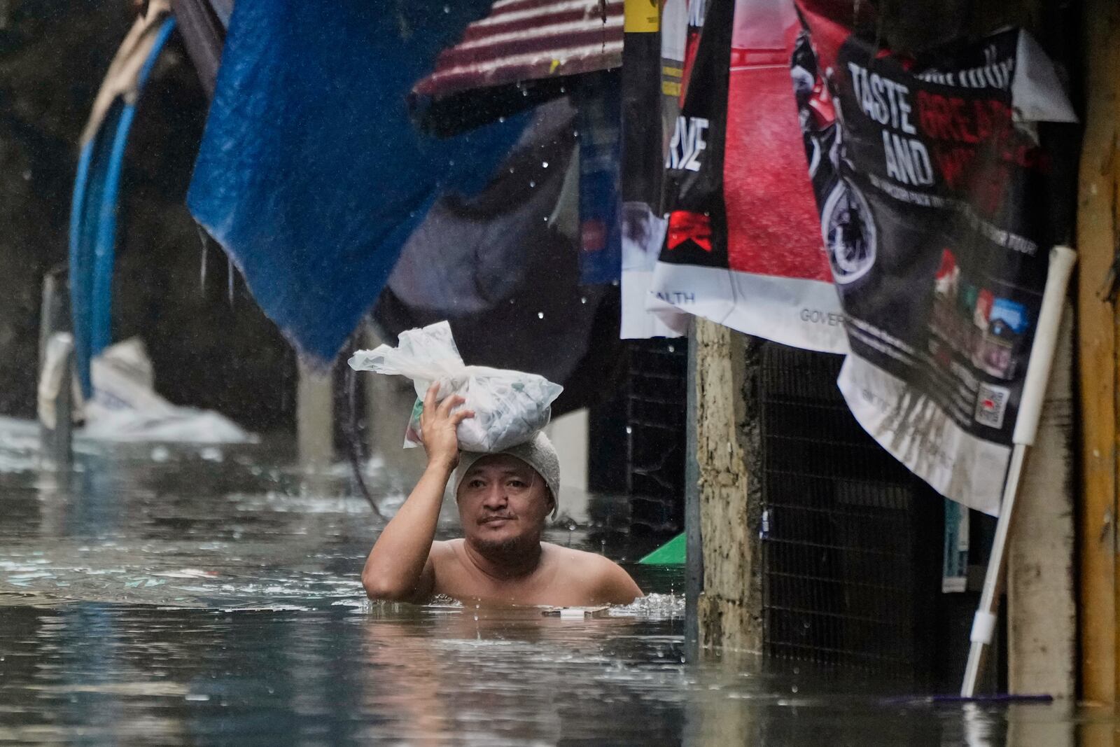 A man wades along chest-deep flood waters following tropical storm Wipha fueled monsoon rains in Quezon city, Philippines on Tuesday, July 22, 2025. (AP Photo/Aaron Favila)