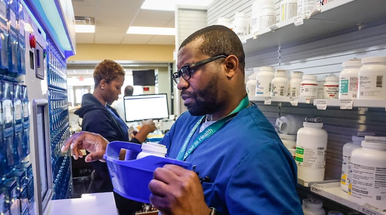 Ziks Family Pharmacy pharmacist intern, Emmanuel Ukattah Jr., fills a robot that disseminates prescriptions at the store on West Third Street on Monday, June 12, 2023. JIM NOELKER/STAFF