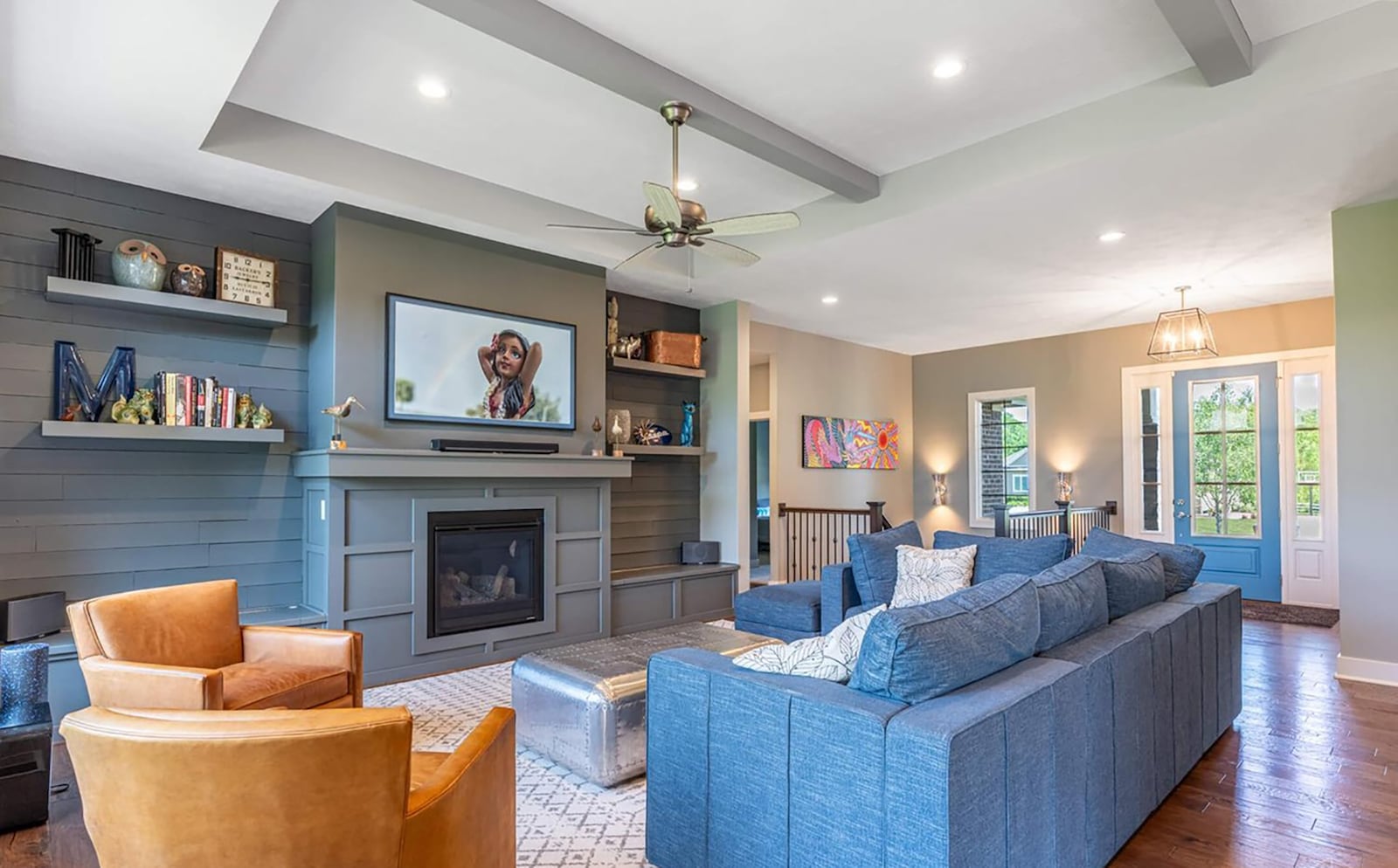 The family room has hardwood flooring, a tray ceiling with beams and a custom gas fireplace with built ins.