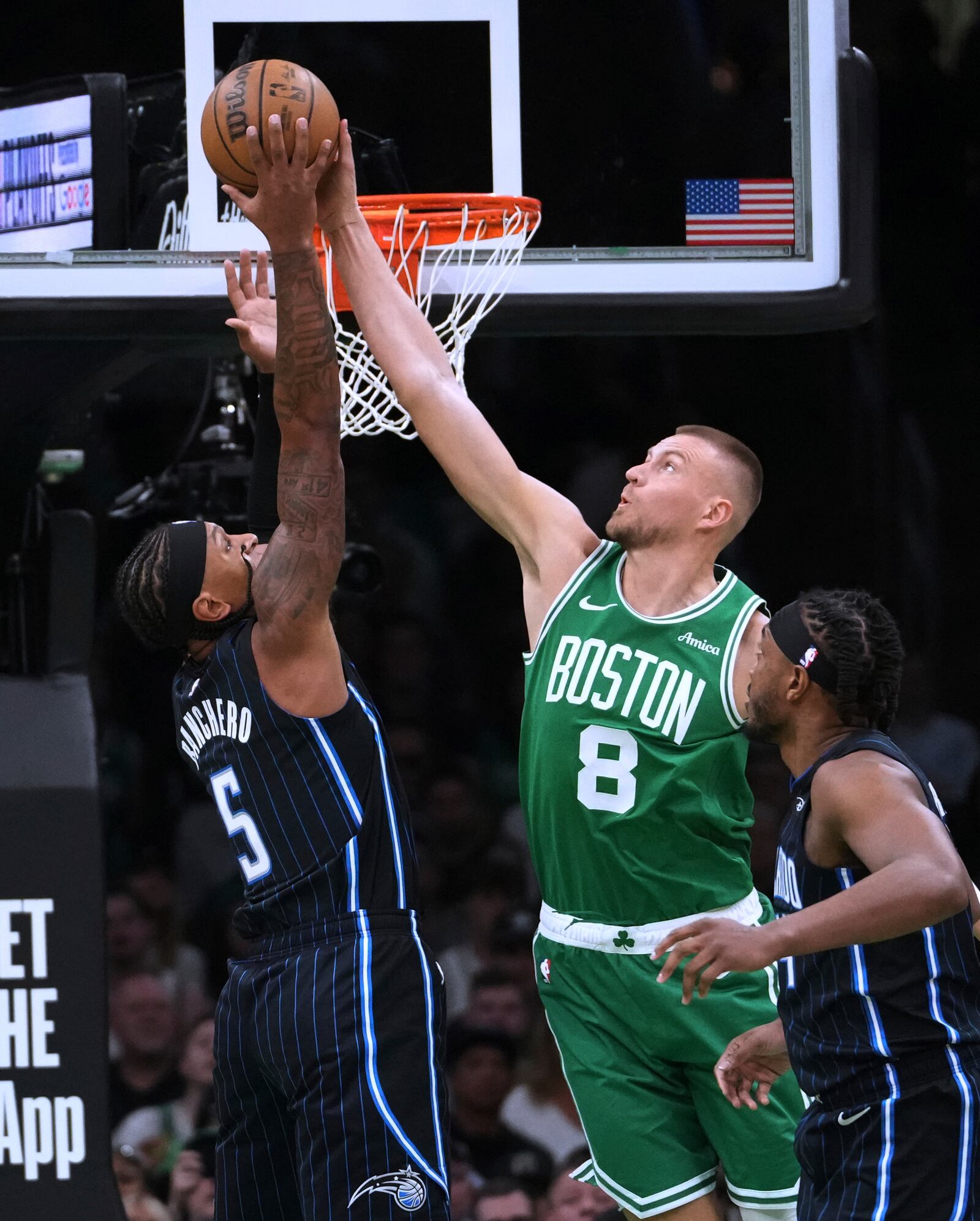Boston Celtics center Kristaps Porzingis (8) blocks a shot by Orlando Magic forward Paolo Banchero (5) during the first half in game 2 of a first-round NBA playoff basketball series, Wednesday, April 23, 2025, in Boston. (AP Photo/Charles Krupa)