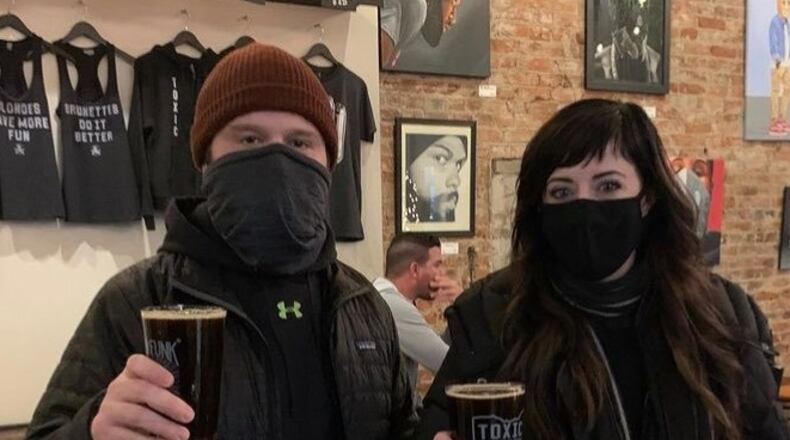 Amber Bromer, the owner of Salon Noir, with her husband, Mark, holding the Salon Noir Porter at Toxic Brew Company.