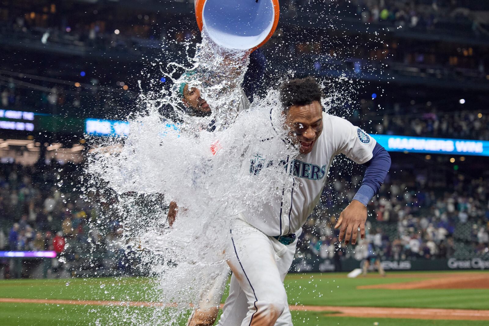 Seattle Mariners' Jorge Polanco is doused with water by J.P. Crawford after his walk off single against Cleveland Guardians during the ninth inning of a baseball game, Saturday, June 14, 2025, in Seattle. (AP Photo/John Froschauer)