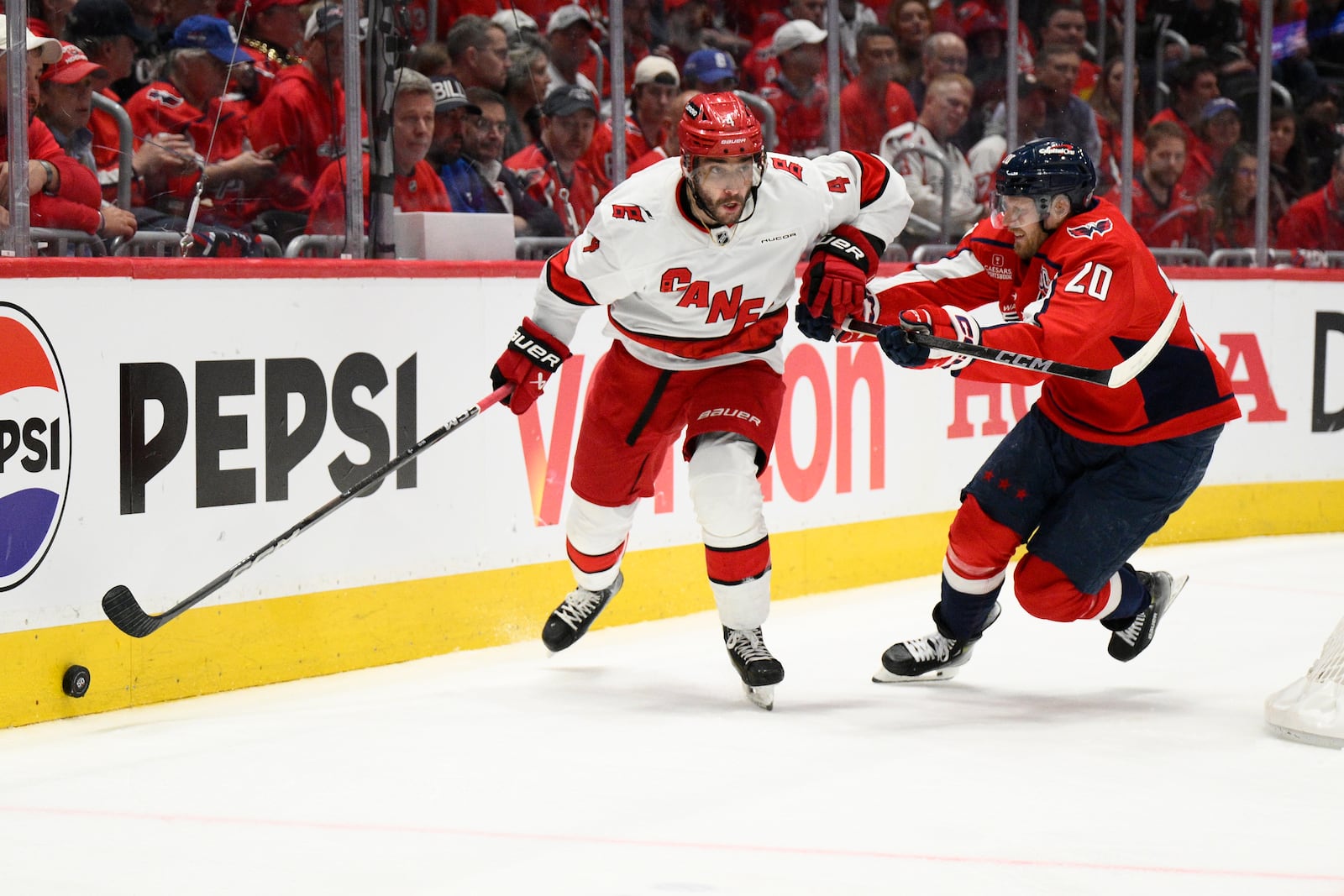Washington Capitals center Lars Eller (20) battles for the puck against Carolina Hurricanes defenseman Shayne Gostisbehere (4) in the first period of Game 2 of a second-round NHL hockey playoff series Thursday, May 8, 2025, in Washington. (AP Photo/Nick Wass)