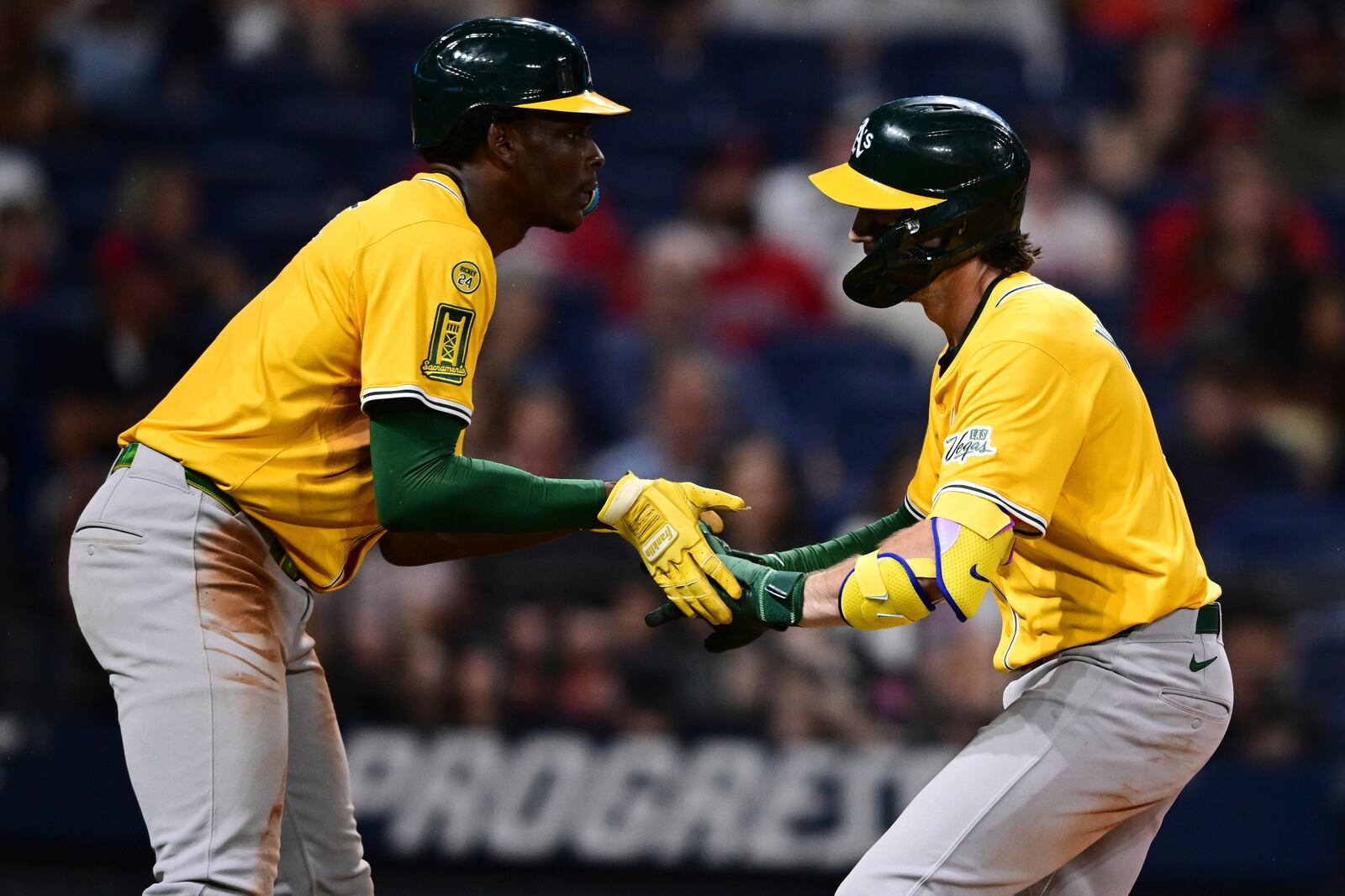 Athletics' Jacob Wilson, right, is congratulated by Denzel Clarke, left, after hitting a two-run home run off Cleveland Guardians relief pitcher Kolby Allard during the ninth inning of a baseball game, Saturday, July 19, 2025, in Cleveland. (AP Photo/David Dermer)
